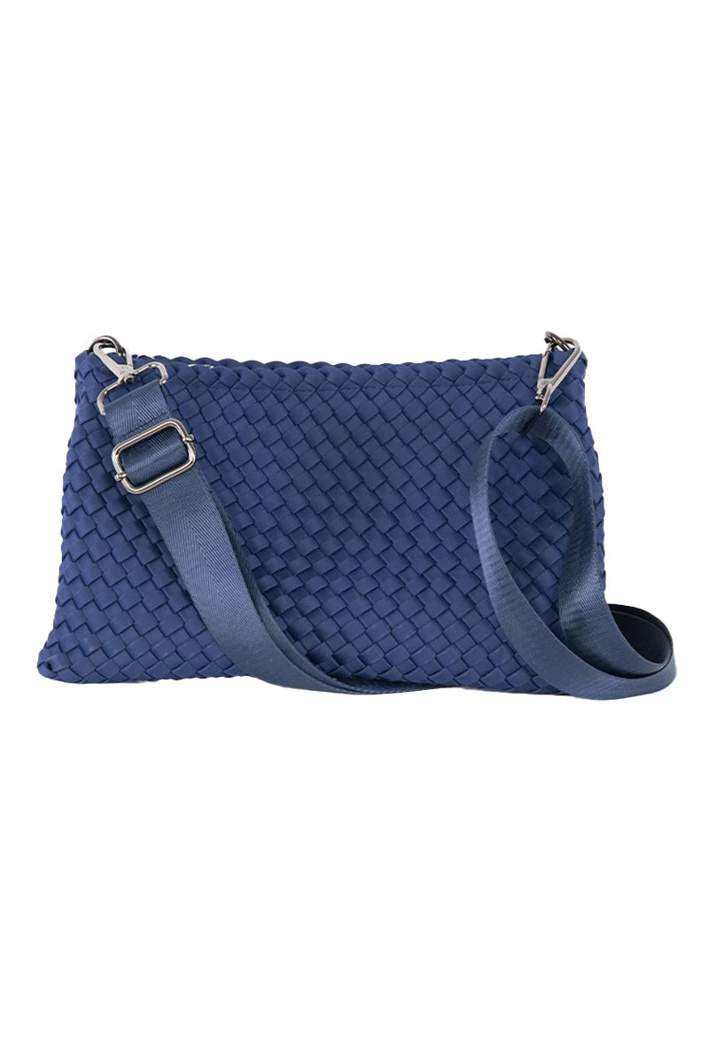 The Katydid Navy Woven Everywhere Small Crossbody is a waterproof neoprene bag with an adjustable strap, blue texture, and sleek silver hardware on the strap attachments.