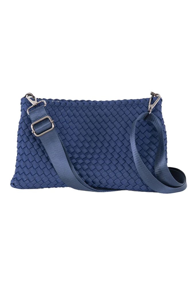 The Katydid Navy Woven Everywhere Small Crossbody is a waterproof neoprene bag with an adjustable strap, blue texture, and sleek silver hardware on the strap attachments.