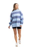 A woman stands and smiles against a white background in the Katydid Light Blue and Navy Striped Mockneck Sweatshirt—an effortless layering piece for fall.