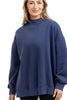 A woman with light brown hair smiles gently while wearing the Katydid Navy Mockneck Sweatshirt for women and black pants, standing against a white background.