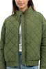 Wearing the Katydid Olive Sporty Diamond Quilted Jacket unzipped over a white top and blue jeans, only the lower half of their face is visible.