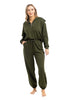 A woman stands barefoot wearing the Katydid Olive Pullover Two-Piece Set, featuring an olive green long-sleeve zip-up hoodie and matching jogger sweatpants. She has her hands in her pockets and smiles at the camera.