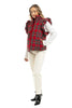 A woman models the Katydid Royal Stewart Plaid Ruffle Puffer Vest, featuring ruffled shoulders, over a white long-sleeve top with white pants and black ankle boots—a festive look against a white background.