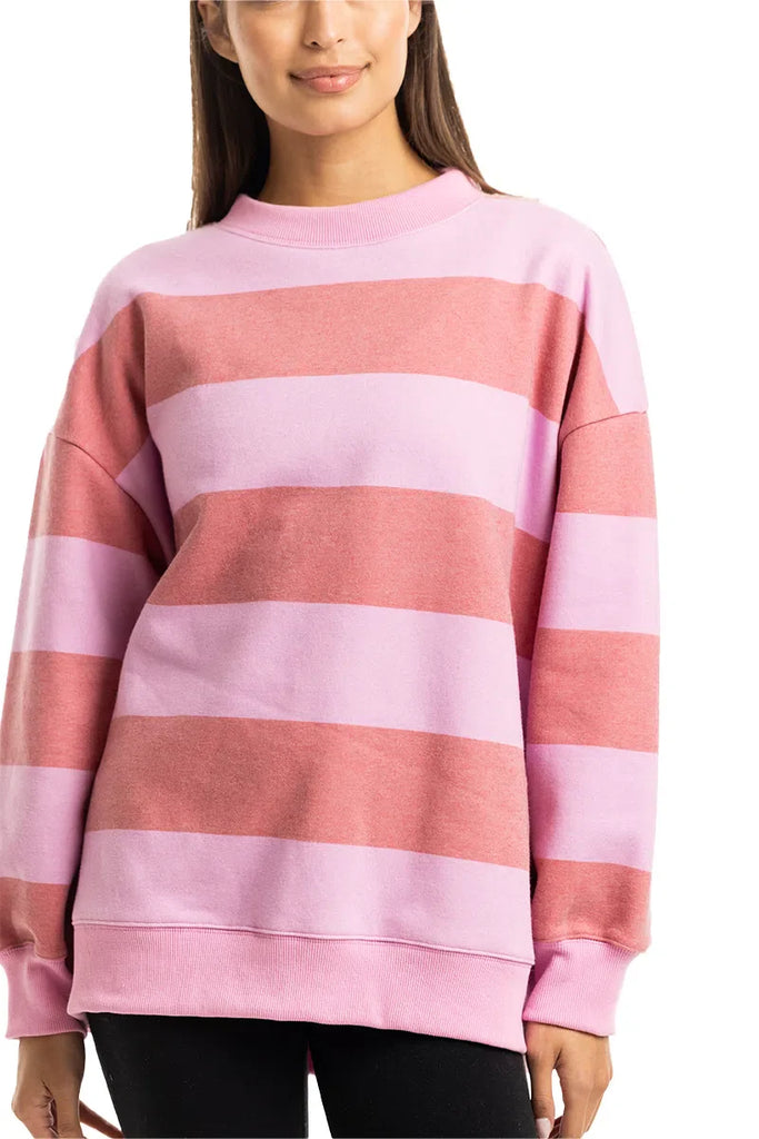 A person models the Katydid Pink and Light Pink Striped Mockneck Pullover, featuring wide horizontal stripes and long sleeves, with their arms relaxed at their sides against a white background. Only their upper body is visible.