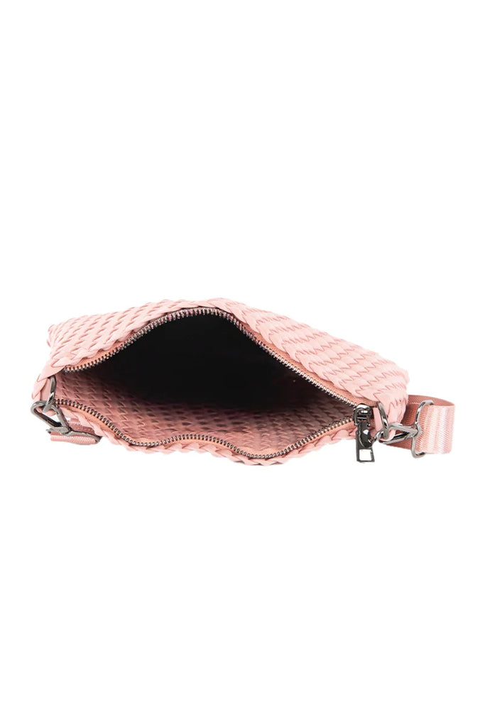 The Katydid Blush Woven Everywhere Crossbody Bag is shown with its zipper open, displaying the interior. It features a diamond-patterned exterior and comes with a detachable, adjustable crossbody strap.