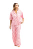 A woman smiles and looks to the side wearing the Katydid Love Joy  Peace Preppy PJ Set—pink animal print pajama pants with a matching button-up top—perfect cozy Christmas pajamas, pictured against a white background.