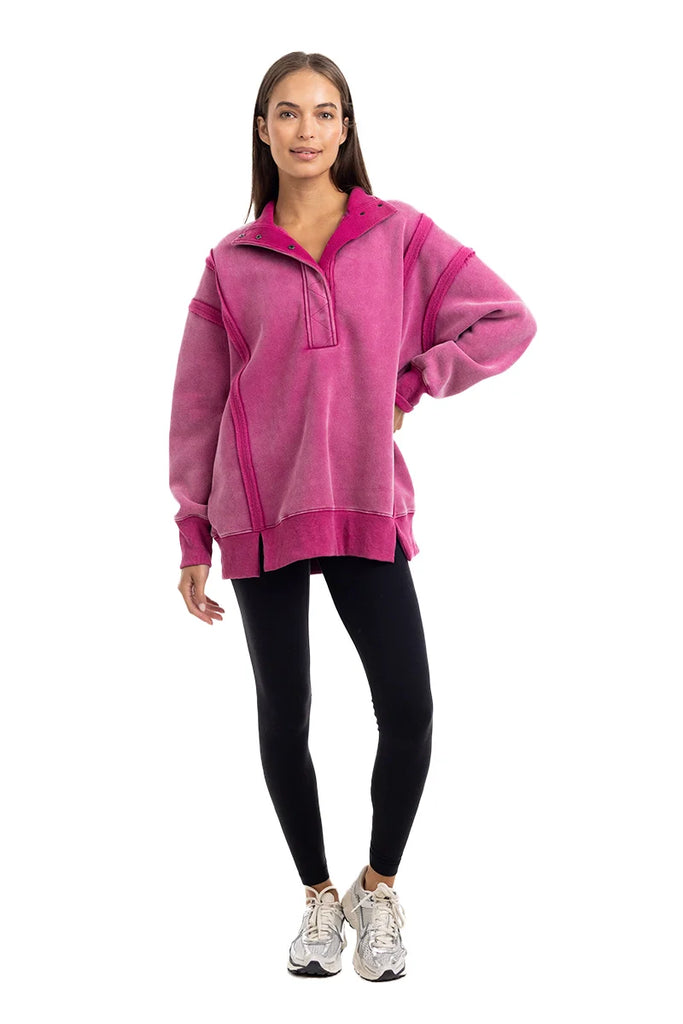 A woman smiles in a Katydid Hot Pink Vintage Wash Pullover Womens sweatshirt, paired with black leggings and white sneakers, against a plain white background.