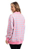 A woman with light brown hair, smiling softly, wears the Katydid Merry  Bright Plaid Mockneck Sweatshirt for women—featuring pink, purple, and white plaid with solid pink trim—paired with black pants.