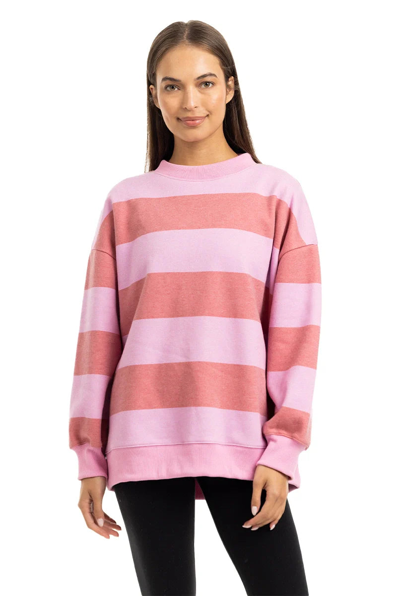 A woman with straight brown hair wears the Katydid Pink and Light Pink Striped Mockneck Pullover and black leggings, standing and smiling at the camera against a white background.
