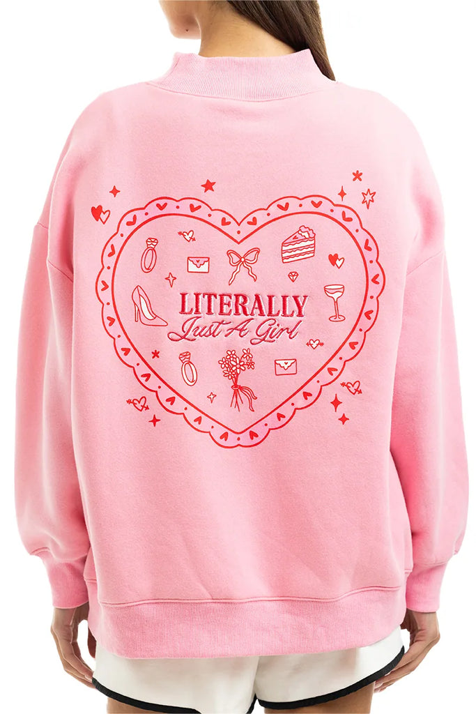 A person wearing the Katydid Literally Just A Girl Mockneck Pullover, a cute pink sweatshirt with a bold red heart, playful icons shoes, cake, lipstick, rings, stars, and the text LITERALLY Just A Girl.