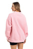 A woman with straight, light brown hair wears the Katydid Pink Essential Mockneck Crew and black shorts, standing against a white background and smiling slightly, with her hands relaxed at her sides.