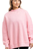A woman models the Katydid Pink Essential Mockneck Crew, a cozy light pink sweatshirt with long sleeves and a high neckline, against a plain white background.