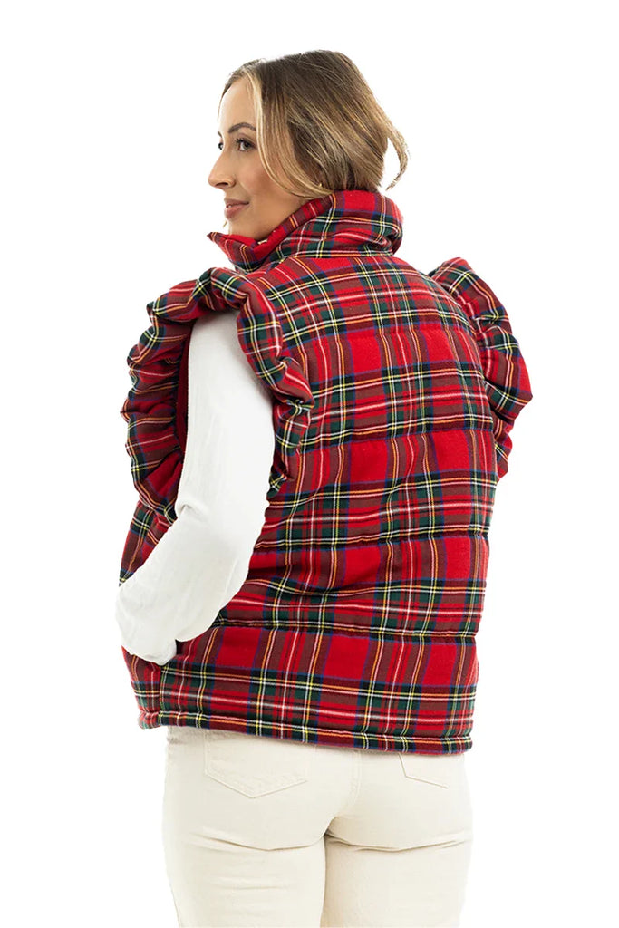 A woman wearing the Katydid Royal Stewart Plaid Ruffle Puffer Vest over a white long-sleeve shirt and cream pants stands facing away—an ideal festive holiday look.