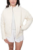 A person wearing the Katydid Cloud White Sporty Diamond Quilted Jacket over a white t-shirt and shorts stands with one hand in their pocket against a plain background.