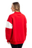 A woman with long, light brown hair wears the Katydid MERRY Womens Mockneck Top in bright red with a white sleeve stripe, standing against a white background and looking slightly to the side.