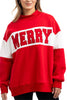 A woman with long hair smiles in the Katydid MERRY Womens Mockneck Top, a red and white sweatshirt featuring MERRY in large red letters across the front, her hands relaxed at her sides.