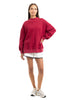 A woman models the Katydid Red Essential Solid Mockneck against a white background, paired with white shorts and sneakers. With long brown hair and a relaxed pose, this cozy pullover is a must-have for your fall wardrobe.