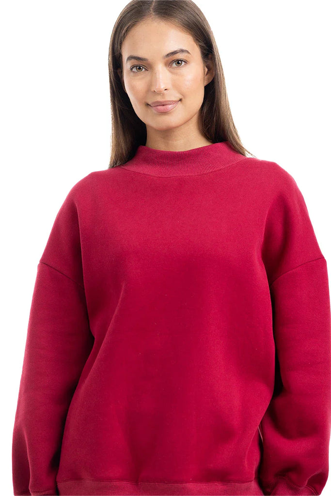 A person with long brown hair wears the Katydid Red Essential Solid Mockneck, smiling softly at the camera in front of a white background—a cozy, stylish pick for your fall wardrobe.