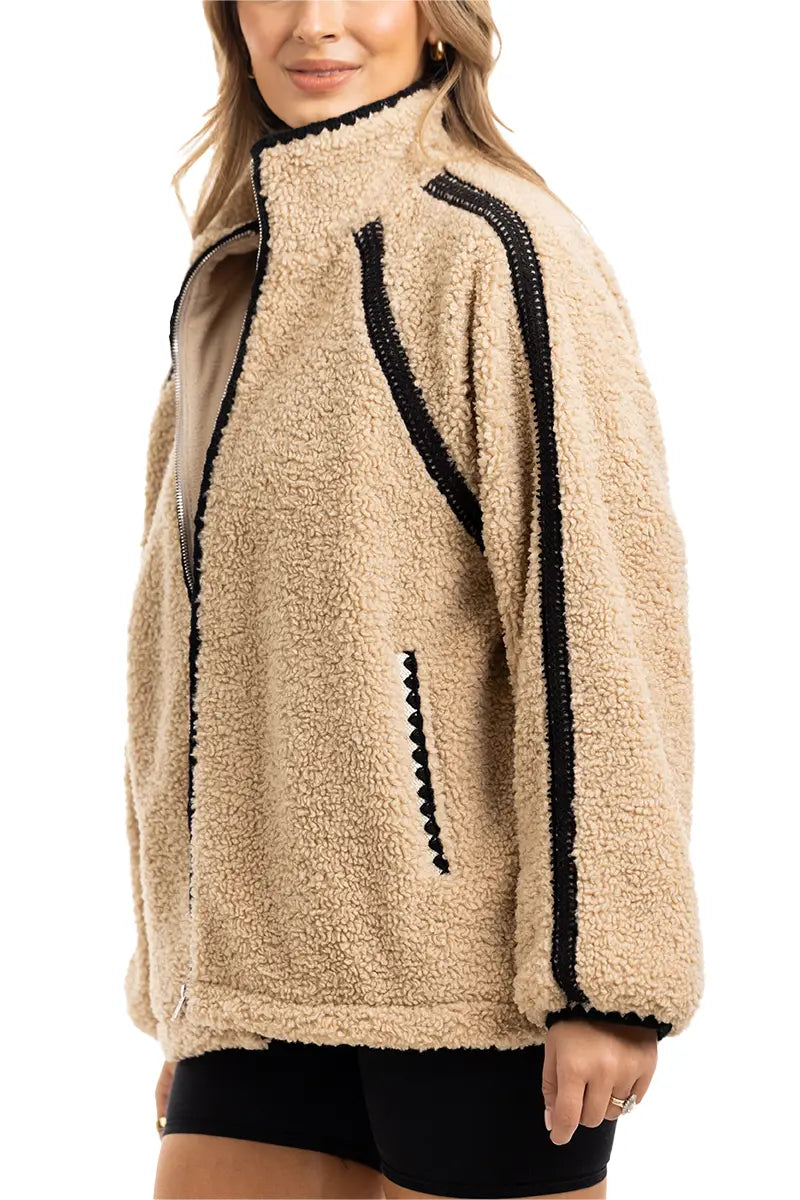A person wears the Katydid Tan Sherpa Lace Trim Jacket, featuring textured sherpa with black lace trim—an ideal cozy layer for chilly fall days.