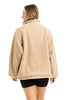 A person faces away, wearing the Katydid Tan Sherpa Lace Trim Jacket with long sleeves and black shorts, set against a white background.