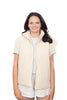 A woman with long brown hair smiles at the camera, wearing the Katydid Cloud White Corduroy Puffer Vest over a short-sleeve gray shirt and light shorts, standing against a plain white background.
