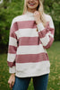 A woman outdoors smiles in the Katydid Wine and White Striped Mockneck Sweatshirt for women, paired with blue jeans. The oversized top adds gameday flair against the blurred green background.