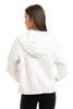 A woman with straight brown hair is seen from the back wearing the Katydid Cloud White Lightweight Hooded Jacket, featuring cinched sleeves and hem, paired with black pants against a plain white background.