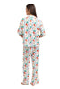 A woman stands barefoot facing away, wearing the Katydid Whimsical Bow Pajamas Set featuring a colorful abstract pattern of red, green, blue, and orange shapes on a white background.
