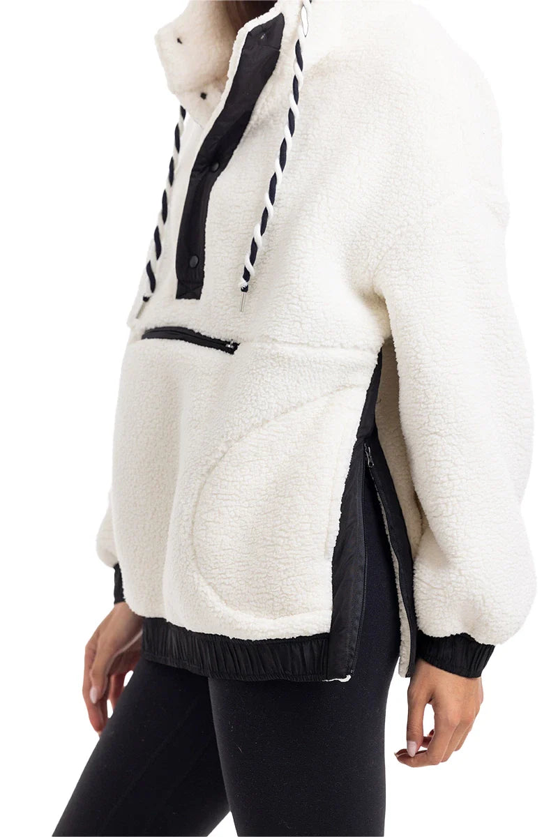 A person wears the Katydid White Womens Two-Toned Pullover Hoodie, featuring black accents, front zipper pocket, drawstring hood, loose fit, and side zippers for comfort—with black leggings.