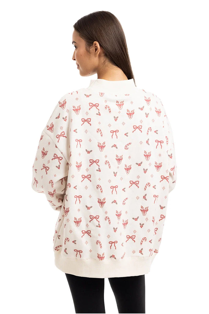 A woman with straight brown hair is seen from behind wearing the Katydid Bow Patch Reindeer Mockneck Sweatshirt for women, featuring pink holiday-themed patterns, paired with black leggings.