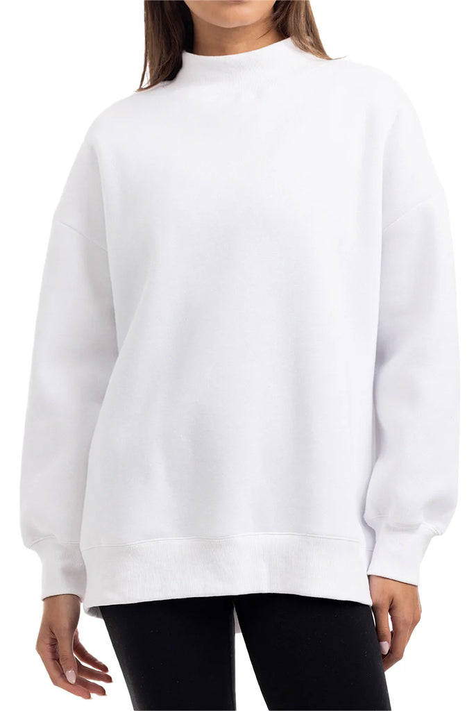 A person is shown from mid-thigh up, facing forward, wearing the Katydid Cloud White Essential Mockneck Sweatshirt with long sleeves and black pants; their face is not visible.