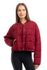 A woman models the Katydid Womens Wine Cropped Quilted Bomber Jacket with black leggings, posing against a white background—a perfect fall look.