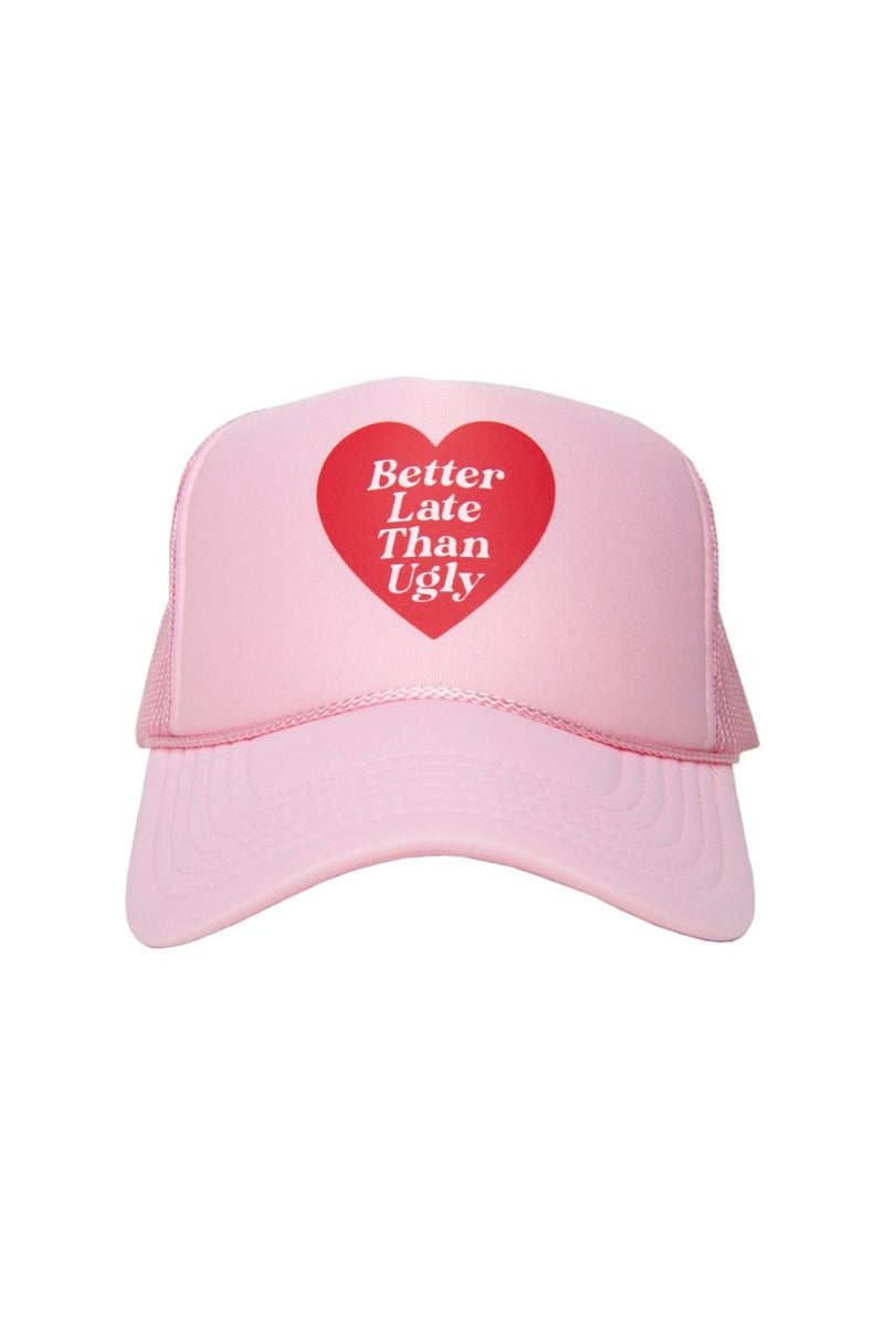 The Katydid Better Late Than Ugly Foam Trucker Cap is a pink women’s hat with a red heart featuring “Better Late Than Ugly” in white. It offers an adjustable snapback for comfort.