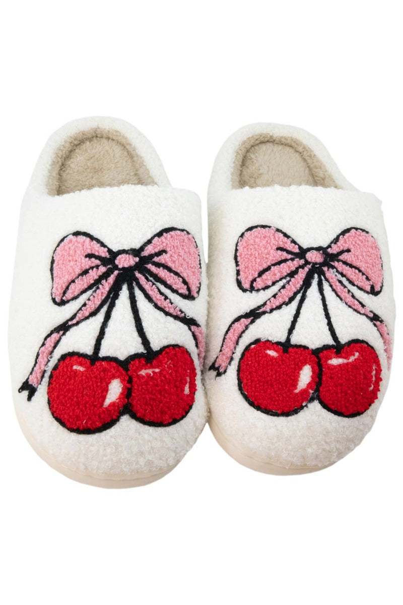 Step into the coquette bows trend with Katydid’s Cherry Bow Slippers Shoes—white fuzzy slippers adorned with embroidered red cherries and pink bows on top.
