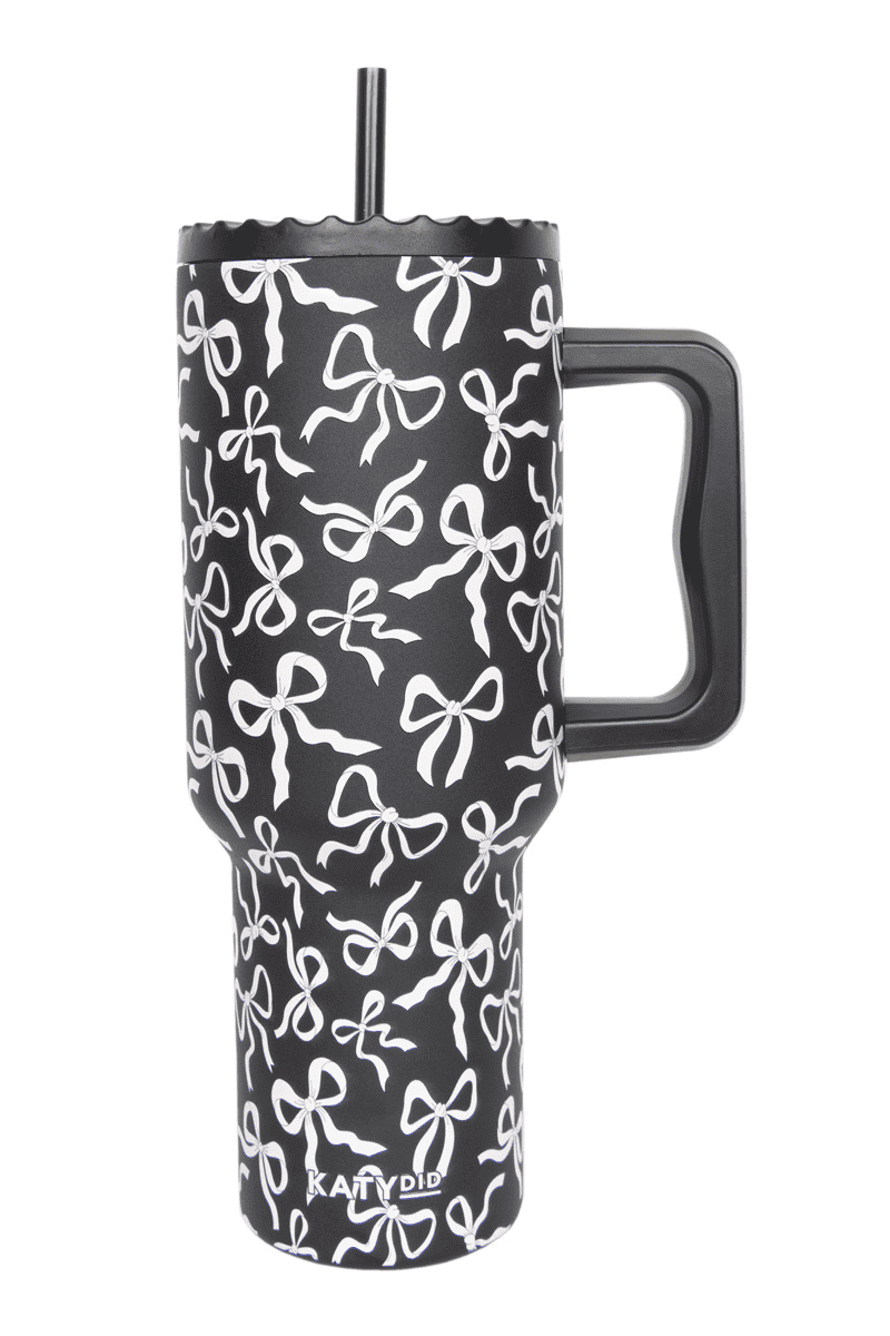 The Katydid Black  White Bows All Over Drink Tumbler Cup is a black insulated tumbler with handle, lid, straw, and stylish white bow pattern. The brand name appears near the bottom of this chic cup.