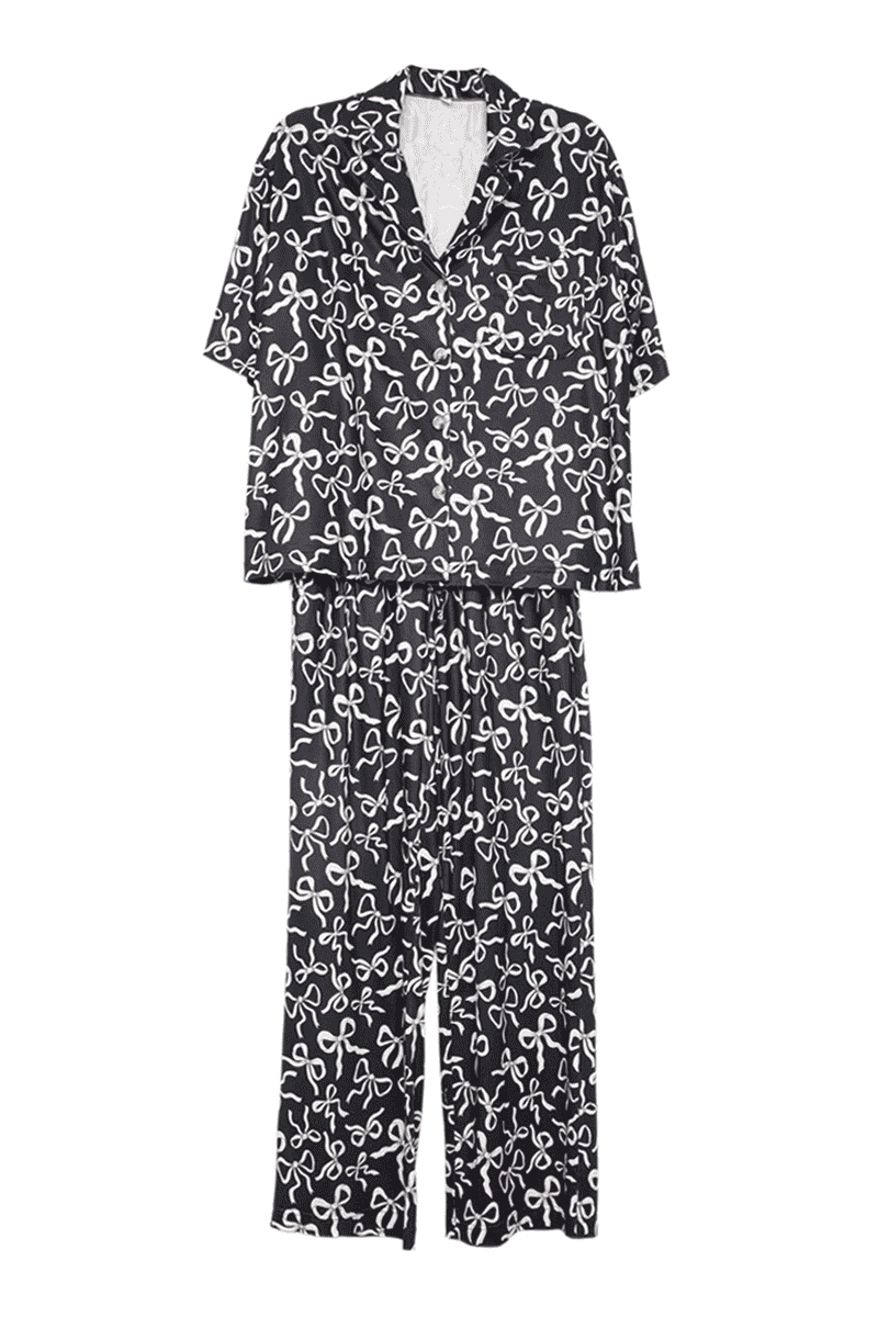 The Katydid Black Bow Print PJ Pants Set features a short-sleeve button-up top and long pants, both decorated with playful black bow prints for charming bedtime style.