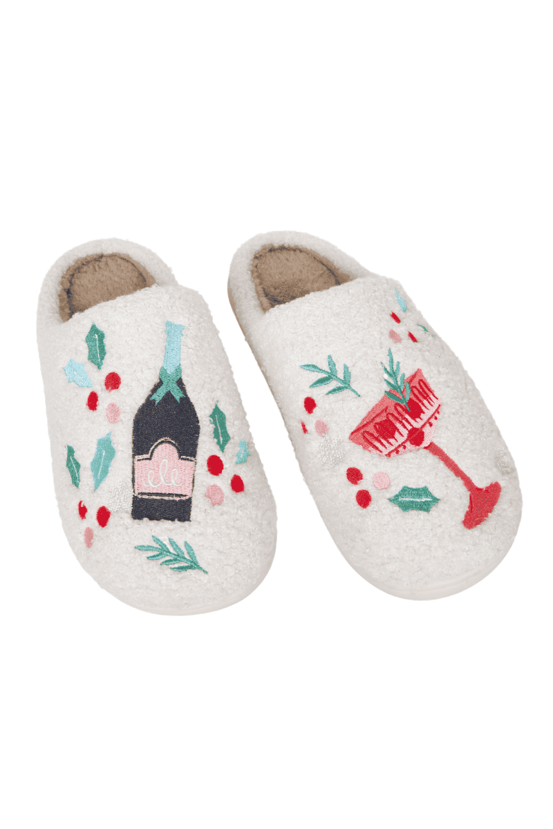 Katydids Holiday Champagne, Coupes  Holly Womens Slippers feature soft white sherpa lining and festive embroidery—one with a champagne bottle and holly, the other with a coupe glass and holly.