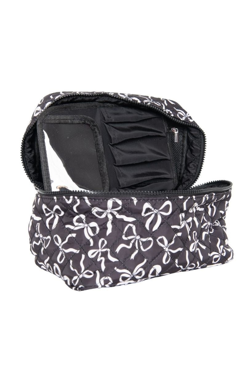 The Katydid Black  White Coquette Bows All Over Makeup Bag features a black quilted design with white bows, plus multiple compartments and a clear pocket inside—perfect for organizing your beauty essentials in coquette style.