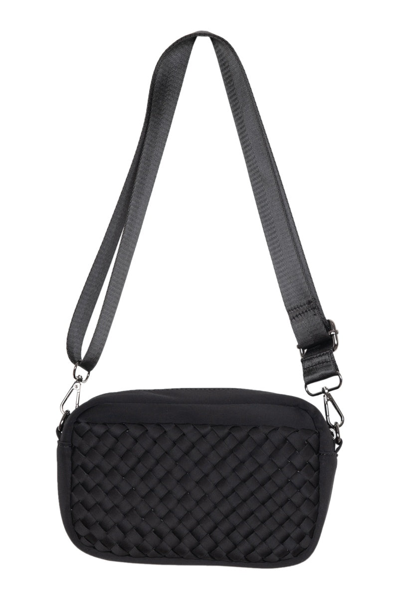 The Katydid Black Woven Womens Crossbody Bag features a basket-weave design, a wide adjustable strap, and a woven front pocket, displayed against a white background.