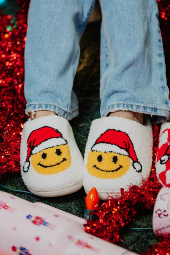 a pair of feet wearing christmas slippers with a santa smiley face on them