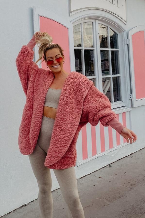 A woman in a pink fuzzy cardigan and leggings