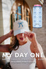 A woman in a white sleeveless top and cream hat with blue bows touches her cap beside a can with blue bows. MY DAY ONE | Bridesmaid Proposal Box by Katydid.com was 65, now 49.95—a perfect bridesmaid gift.