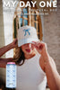 A woman in a white sleeveless top and cap with blue bows adjusts her hat. Text above features the Katydid.com My Day One Bridesmaid Proposal Box—was 65, now 49.95. A blue bow can makes this the perfect bridesmaid gift idea.