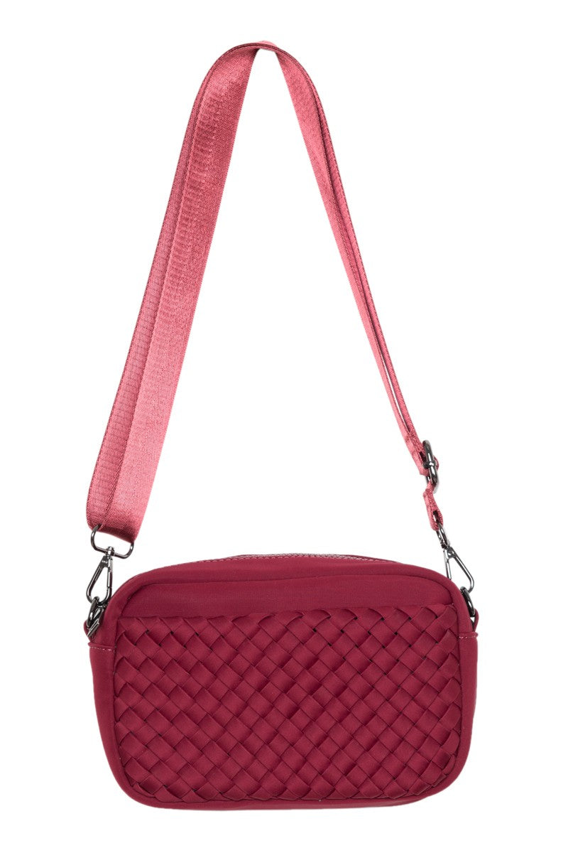 The Katydid Wine Woven Crossbody Bag for Women is a small rectangular bag featuring a red woven front and a wide matching strap with metal clasps.