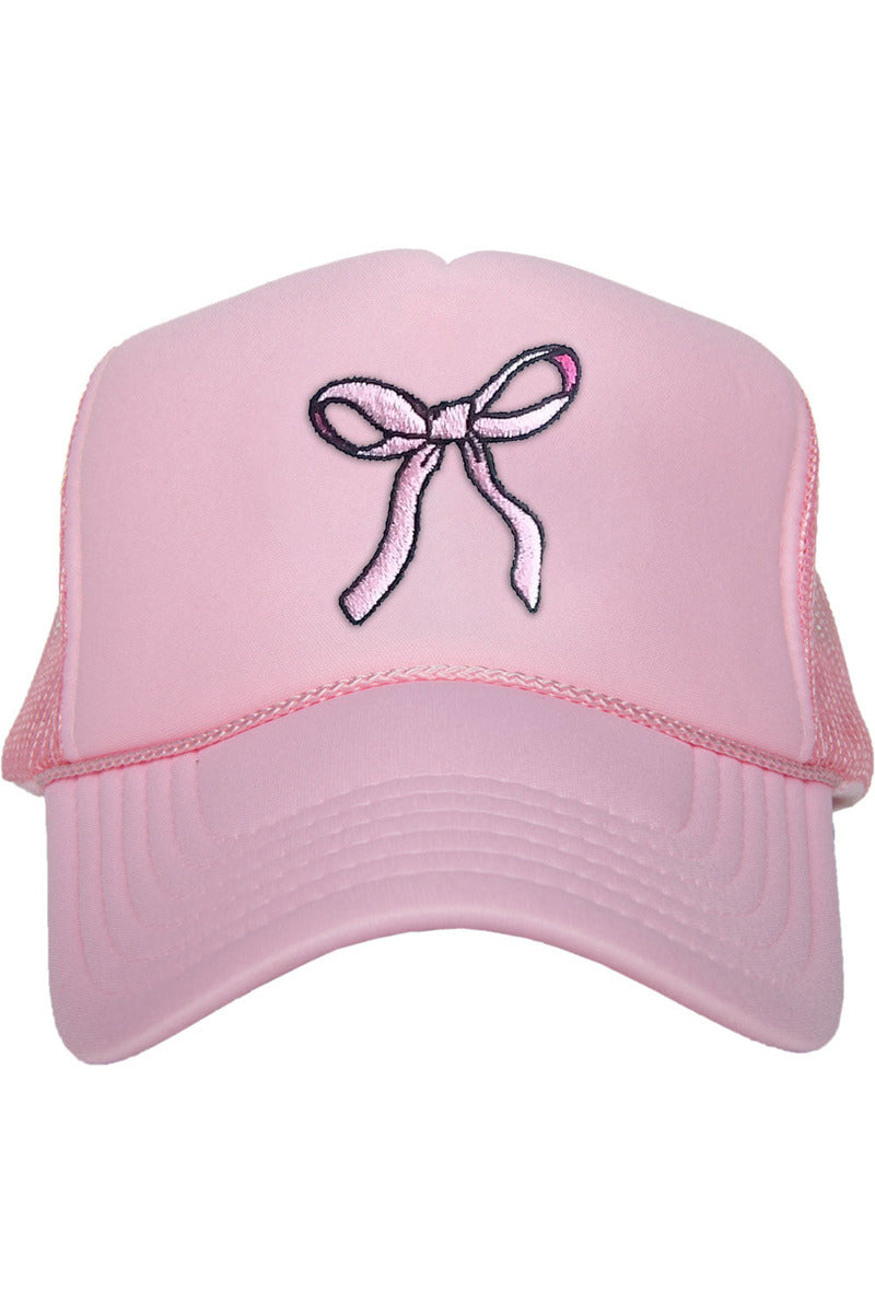 The Katydid Coquette Pink Bow Foam Trucker Hat features a light pink color, breathable mesh back, and an embroidered pink bow on the front for a cute, stylish look.