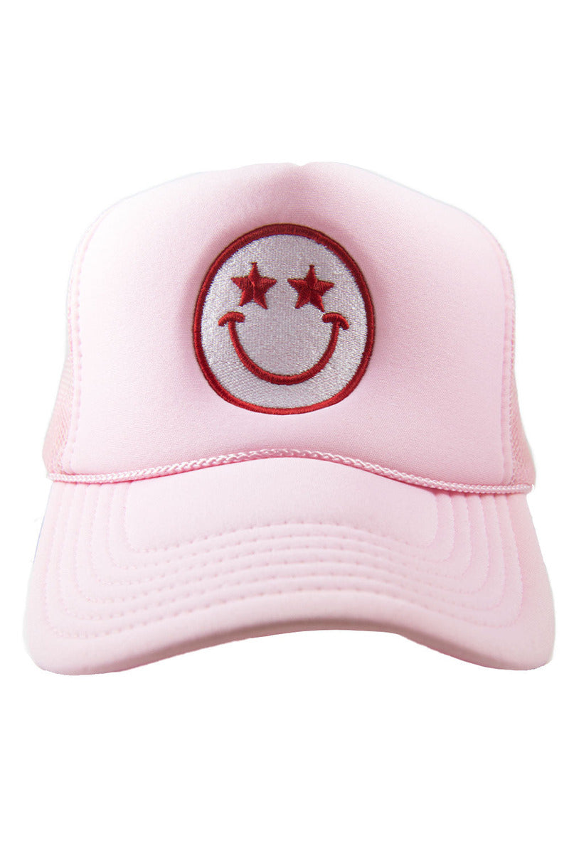 A pink foam trucker hat with a starry eyed smiley face on it