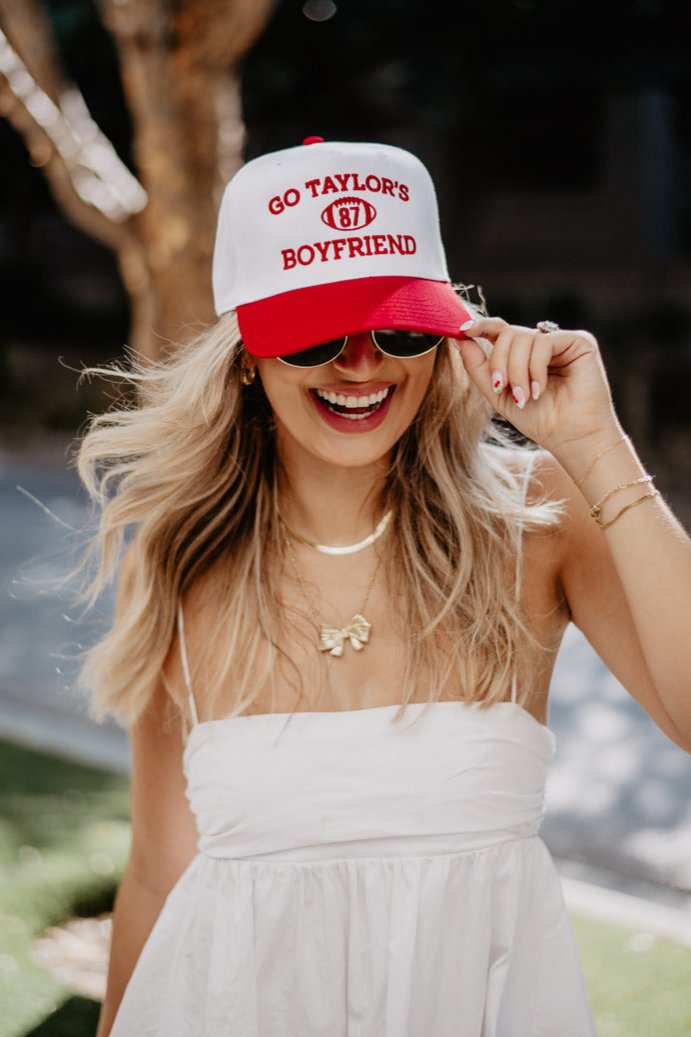 A woman wearing a red and white go taylor's boyfriend hat and sunglasses