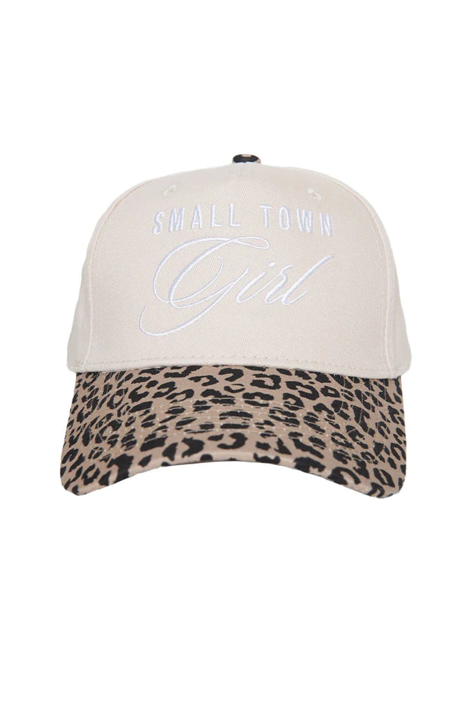 The Katydid Small Town Girl Vintage Trucker Hat for Women features beige fabric, white embroidered front text, and a curved brim with a stylish brown and black leopard print.