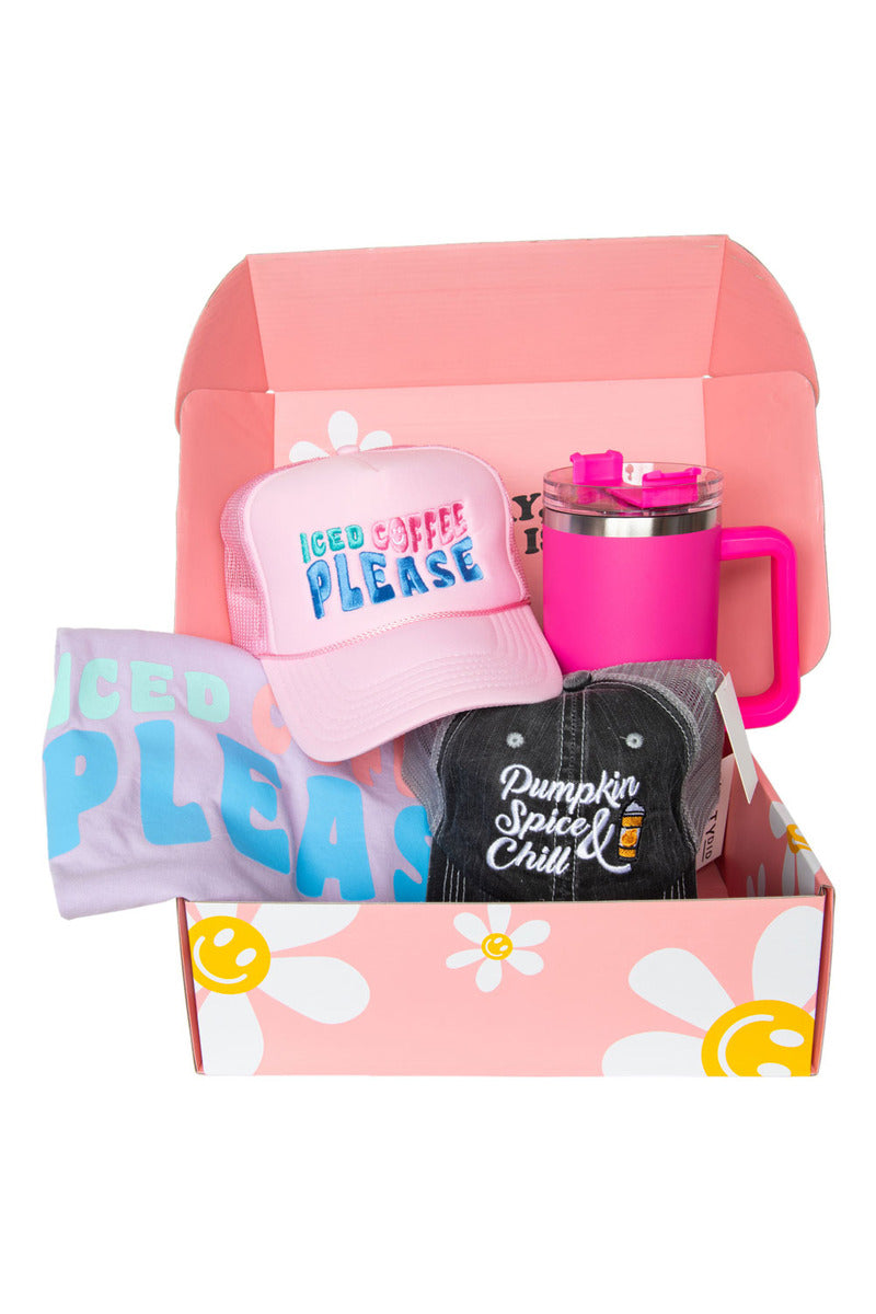 Pink gift box with flower design containing a pink and black hat, pink travel mug, and pastel shirt.