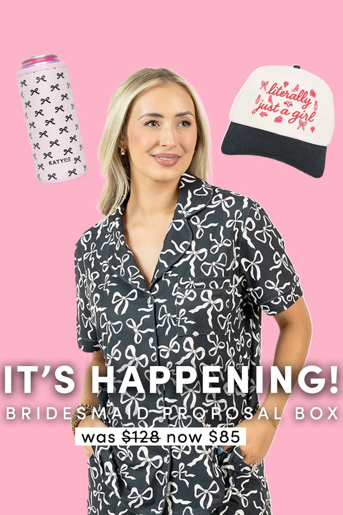 A woman in black-and-white bow pajamas stands before a pink background. Floating nearby are a can cooler and cap. Text below: ITS HAPPENING | Bridesmaid Proposal Box by Katydid.com—perfect bridesmaid gift set, was 128, now 85.